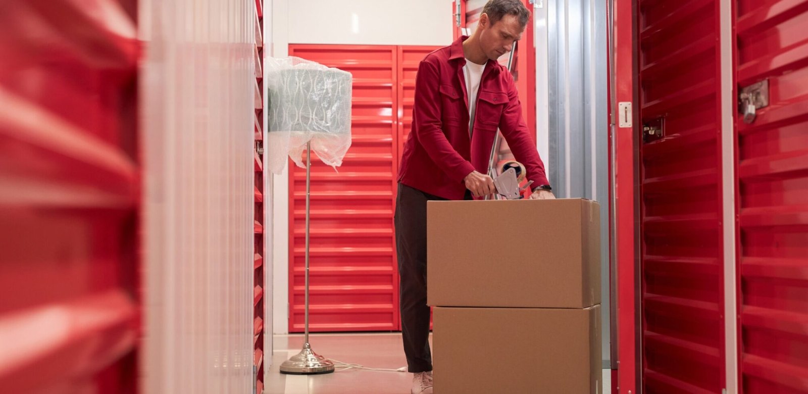 man taping cardboard boxes in warehouse 92f45t